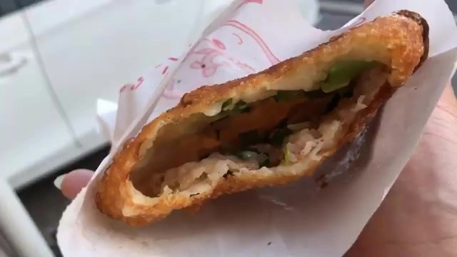 燒餅剖面特寫，露出滿滿的肉末與蔥花內餡，外皮金黃酥脆