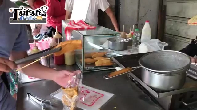 老闆在攤位前為顧客現場打包剛炸好的黑輪