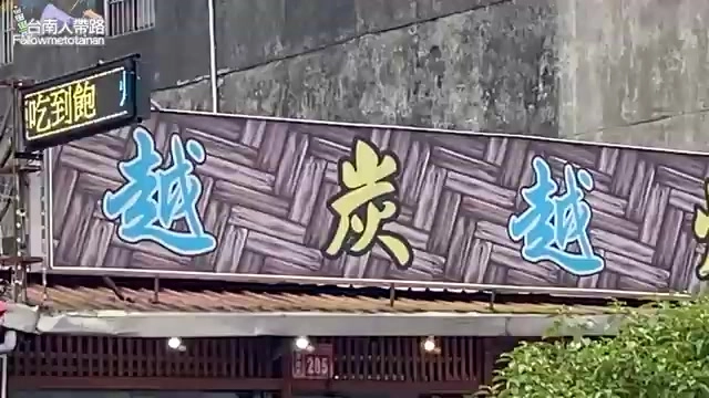 店家招牌以編織紋理底色搭配藍色「越炭越」大字，一旁綠底霓虹燈寫著「吃到飽」