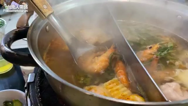 不鏽鋼鍋中的火鍋湯底正在滾煮，可見新鮮蝦子、玉米與蔬菜料理，蒸氣瀰漫