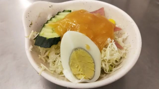 附餐沙拉盛裝高麗菜絲、小黃瓜與水煮蛋，淋上千島醬