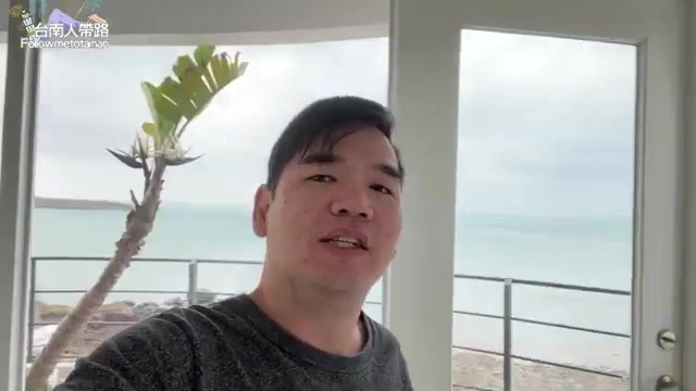 阿波站在候鳥潮間帶民宿窗邊自拍,落地窗外270度環繞湛藍海景一覽無遺