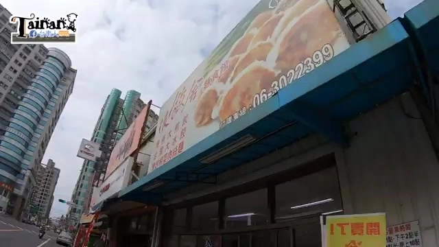 店面外牆掛著大型煎餃廣告招牌,寫著訂購專線電話號碼,藍色遮陽棚下是店家入口
