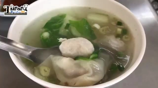 白色瓷碗盛著清湯,內含魚丸與餛飩,搭配青菜與蔥花,湯匙插在碗中