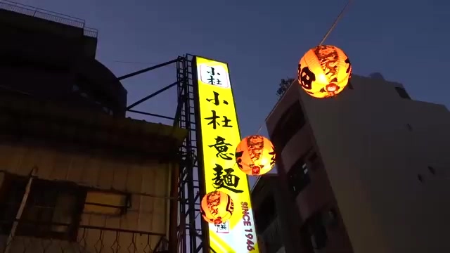 小杜意麵店招牌與燈籠在夜色中點亮，招牌上標示著自1946年創立至今