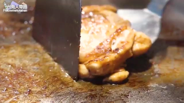 鐵板上正在煎烤的雞腿肉，色澤金黃焦香，刀子正切開肉塊