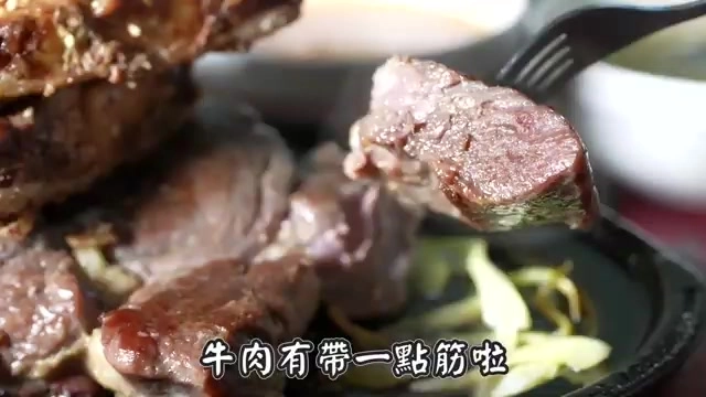 特寫用叉子夾起的牛肉塊，切面帶著粉紅色澤與少許筋絡，肉質紋理清晰