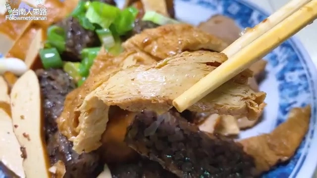 筷子夾起深色滷豆皮,搭配豆乾與蔥花,色澤醬紅入味