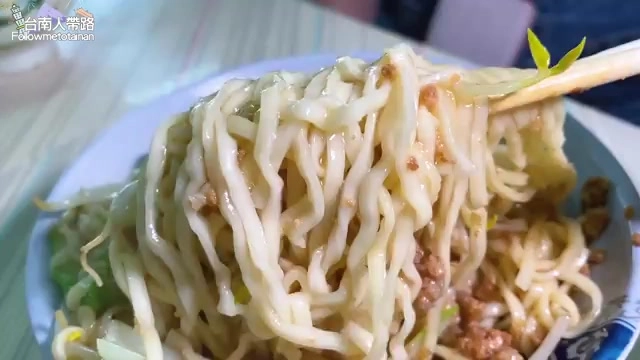 筷子夾起一大把意麵,麵條裹著醬色油亮的醬汁,搭配肉燥與豆芽菜