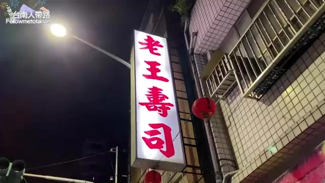 夜晚拍攝的紅色招牌上寫著「老王壽司」,一旁掛著紅色燈籠