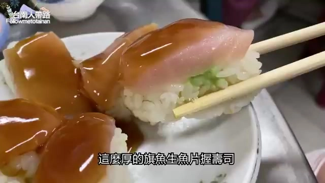 筷子夾起厚切的旗魚握壽司,魚肉紋理清晰,淋上醬汁