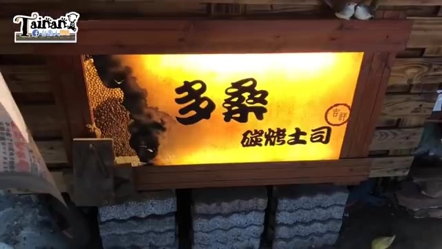 店家招牌在夜間點亮,木框搭配燈箱寫著「多桑碳烤土司」