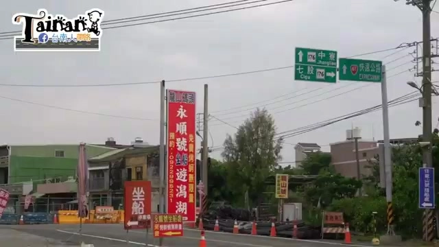 永順號招牌立於路口,紅底白字寫著「永順號 坐船遊潟湖」,一旁交通指示牌標示七股方向