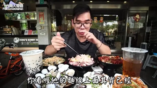 阿波夾起麻油小卷麵線品嚐,一旁擺滿其他招牌菜色
