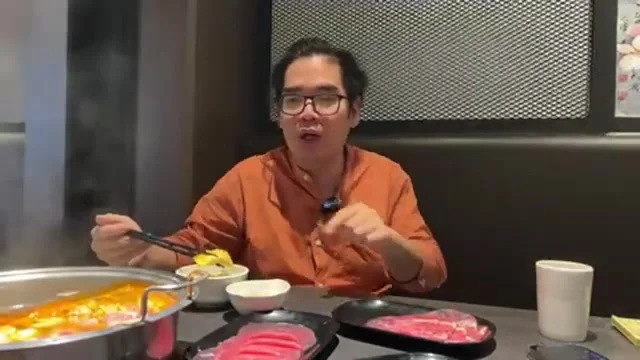阿波手持筷子,面前擺著滾燙冒著蒸氣的火鍋與待涮生肉盤