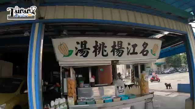 路邊攤位招牌，白底黑字寫著「名江楊桃湯」，攤車上擺放不鏽鋼冷藏設備與飲料杯