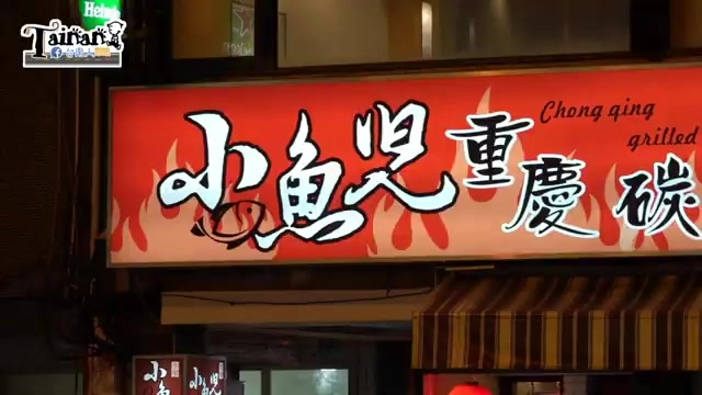 店家招牌，紅底白字寫著「小魚兒重慶碳烤」，配上火焰圖樣裝飾，招牌下方是店面入口