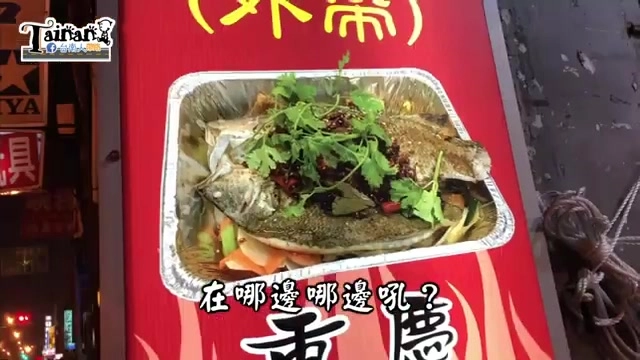 紅色招牌上印著烤魚外帶餐盒照片，鋁箔盒裝著整條烤魚，鋪滿香菜與辣椒點綴