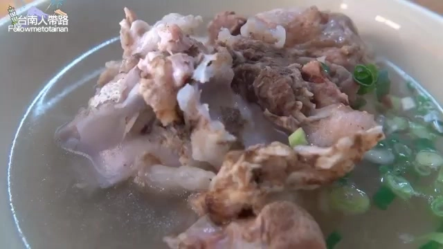白色瓷碗盛著燉煮軟爛的大骨與豬雜料，湯色清澈搭配蔥花點綴