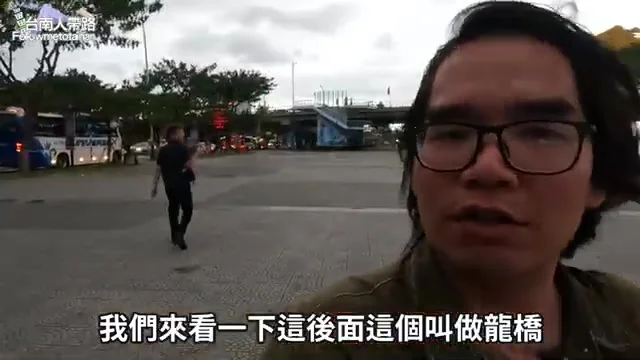 阿波站在廣場上,指向後方遠處的龍橋