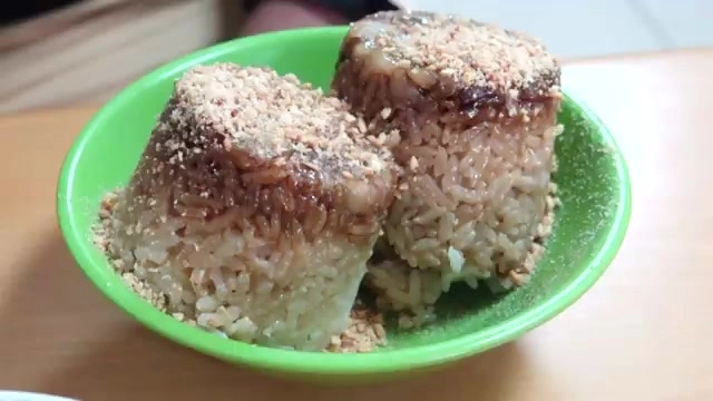 特寫畫面呈現兩顆米糕，表面淋著醬油膏光澤，灑滿花生粉，米粒濕潤不乾