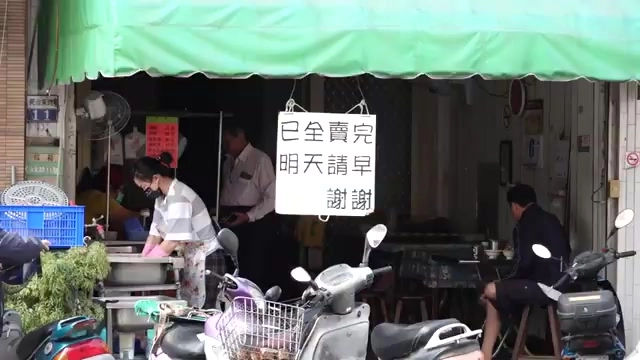 店門口掛著「已全賣完 明天請早 謝謝」的手寫牌子，店家正在收拾攤位