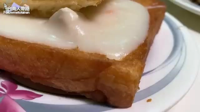 厚片吐司切面特寫，頂端覆蓋著濃稠白色內餡，質地滑順