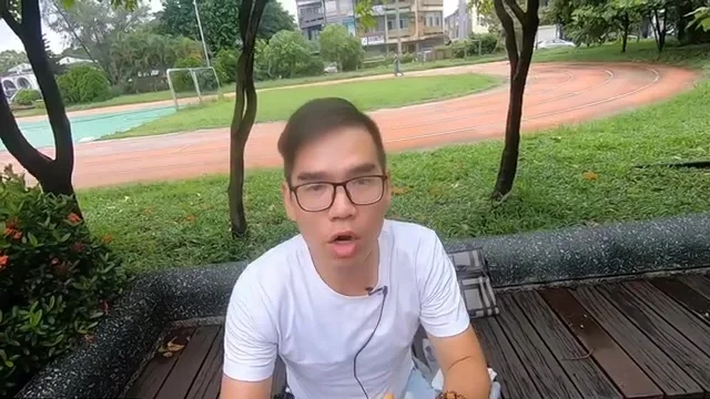 阿波坐在公園長椅上，向鏡頭介紹韭菜盒子的內餡厚度