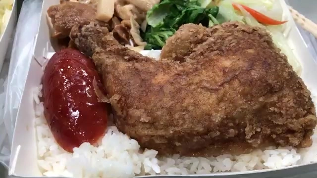 便當盒中盛著炸雞腿與白飯,搭配番茄醬、燙青菜與炒肉絲配菜