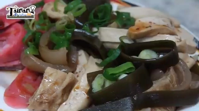 白色瓷盤盛裝著涼拌豆干、海帶、洋蔥與嫩雞肉絲，撒上蔥花點綴