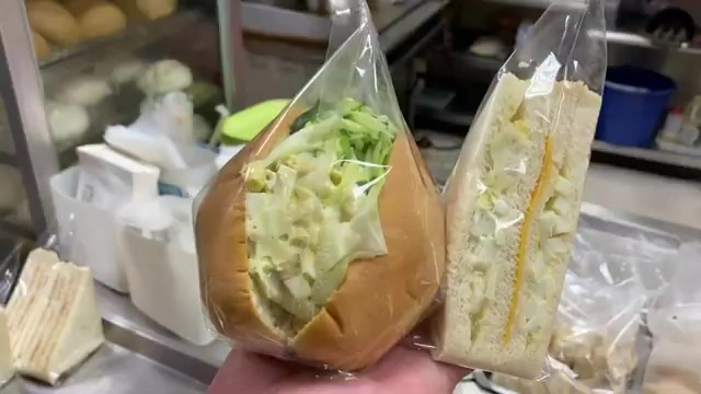 手拿蛋沙拉三明治與蛋沙拉潛艇堡，內餡飽滿到從吐司邊緣溢出