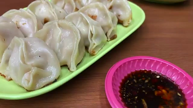 盤中擺著多顆煎餃，搭配粉紅色小碟裝著特調沾醬