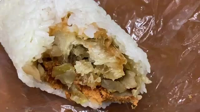 剖開的飯糰內部可見酸菜與油條餡料，包裹在粒粒分明的白米飯中