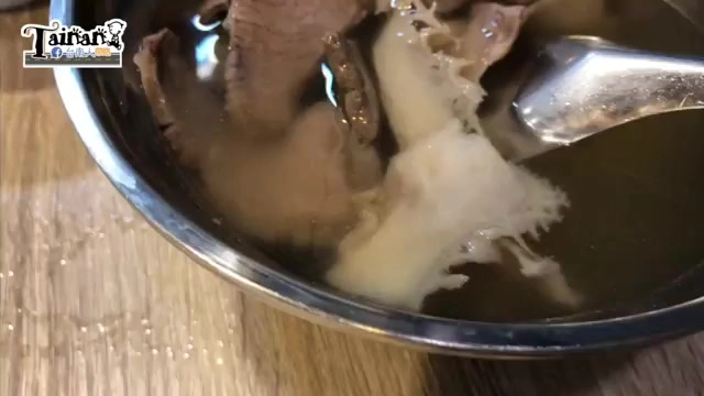 不鏽鋼碗盛著牛肉湯,湯色清澈,牛肉片與泡沫浮於湯面