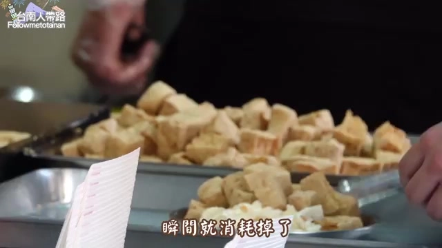 鐵盤上盛滿剛炸好的臭豆腐塊,老闆的手正在整理