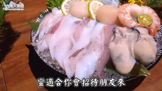 白色瓷盤盛裝花枝、牡蠣、蝦子與干貝等多樣海鮮，鋪在碎冰上並點綴檸檬片