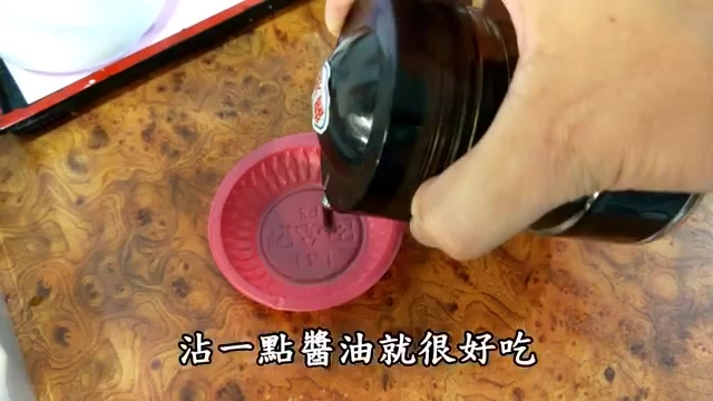 手持醬油瓶正倒入紅色小碟中，準備沾水餃享用