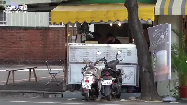 街邊小吃攤位掛著黃色遮陽篷，菜單清楚列出各式口味與價格
