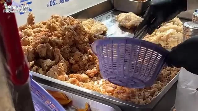 店家鐵盤上滿滿剛炸好的雞排與雞丁,老闆娘正在裝袋
