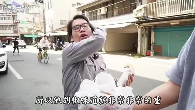 阿波站在店門口街邊,手拿紙包雞排準備試吃