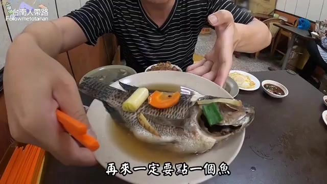 整條吳郭魚盛盤上桌,搭配紅蘿蔔與蔥段點綴,湯汁清澈
