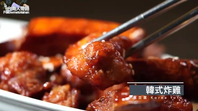 筷子夾起裹著紅色醬汁的韓式炸雞塊，色澤油亮誘人