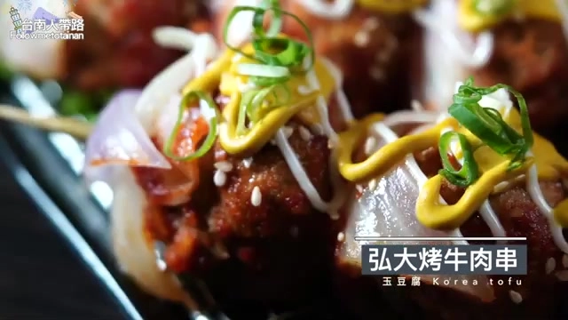 烤牛肉串串沾滿紅色醬汁，淋上黃色芥末醬並點綴蔥花與芝麻
