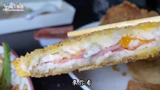 切開的炸物剖面,可見夾層裡的火腿片與融化的起司、蛋黃層層堆疊