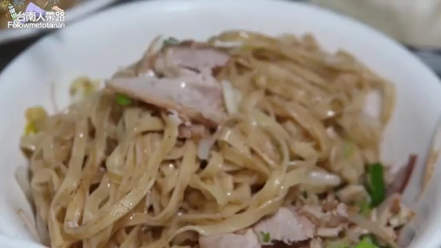 白色碗中盛著拌好的意麵，搭配肉片與蔥花，色澤油亮