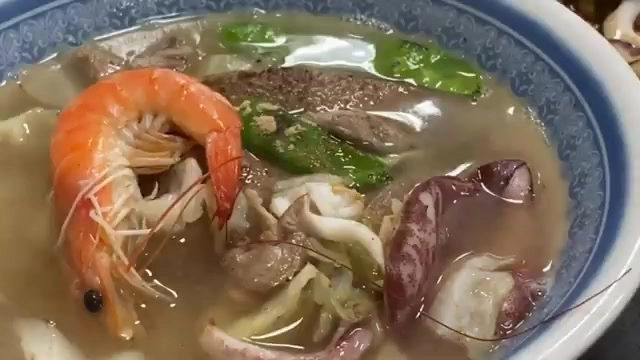 湯碗裡盛著蝦子、花枝、豬肝等豐富配料的湯麵，湯色清澈鮮甜