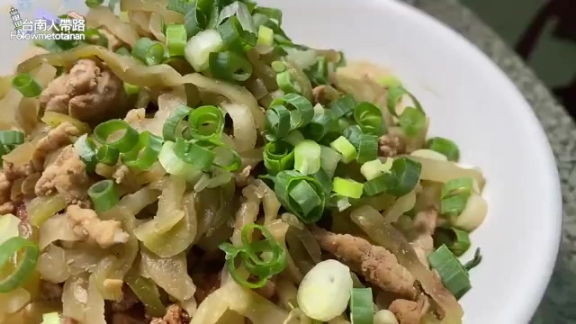 白色大碗裡盛滿拌著肉燥與大量青蔥的麻醬麵，份量堆得像小山