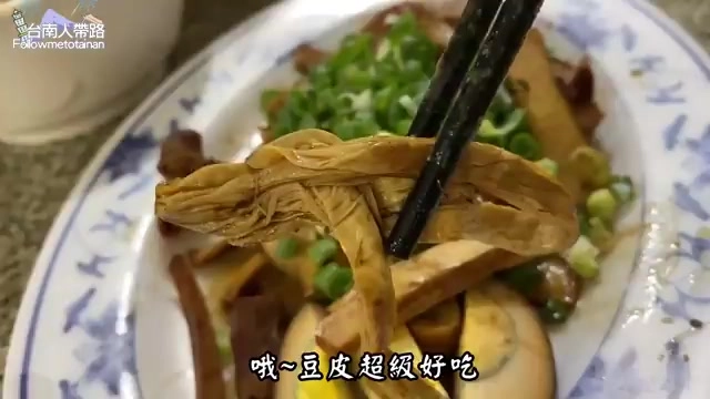 盤中盛著滷豆皮、滷味與青蔥點綴，筷子正夾起一片豆皮