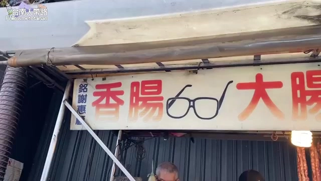 斑駁招牌上寫著「香腸大腸」,中間畫著一副黑框眼鏡圖案作為店家識別
