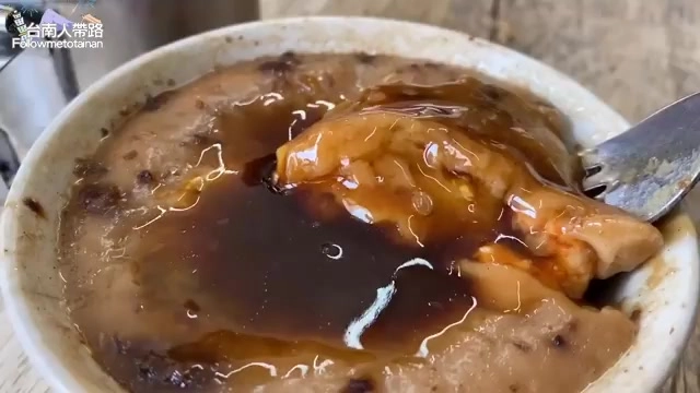 碗粿盛在瓷碗中，淋上甜醬油，露出裡頭包裹的肉塊與配料